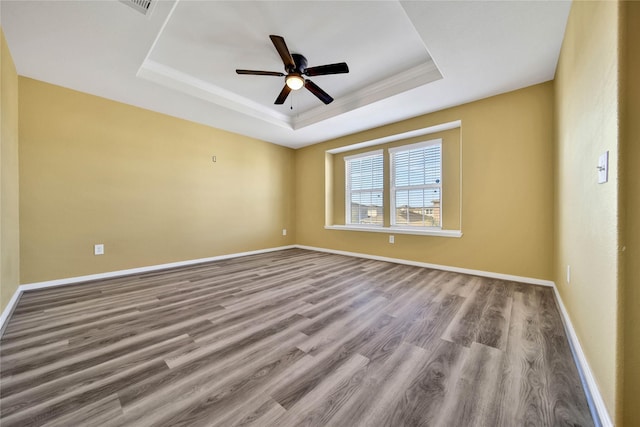 unfurnished room with a ceiling fan, baseboards, a tray ceiling, and wood finished floors