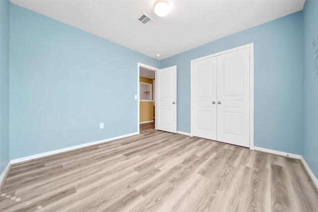 unfurnished bedroom with baseboards, a closet, visible vents, and light wood-style floors