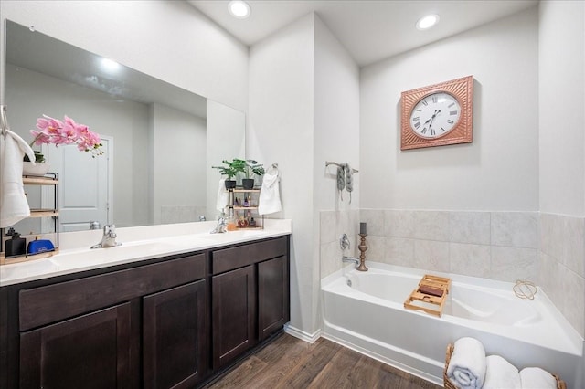 bathroom with hardwood / wood-style flooring, vanity, and a tub to relax in