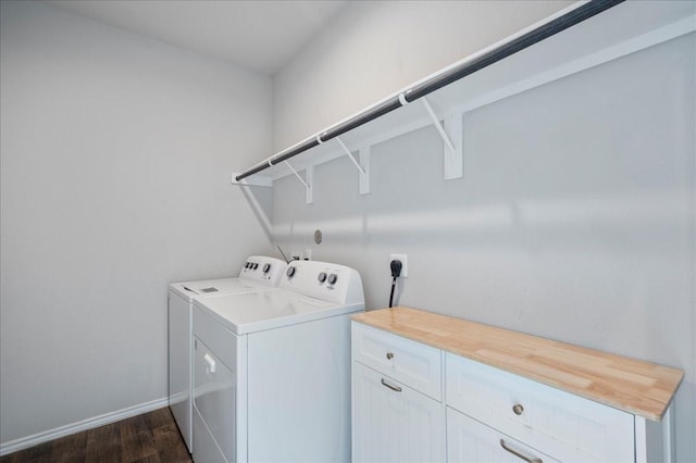 clothes washing area featuring cabinets, washer and dryer, and dark wood-type flooring