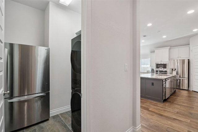 kitchen featuring white cabinetry, sink, a kitchen island with sink, light stone counters, and stainless steel appliances