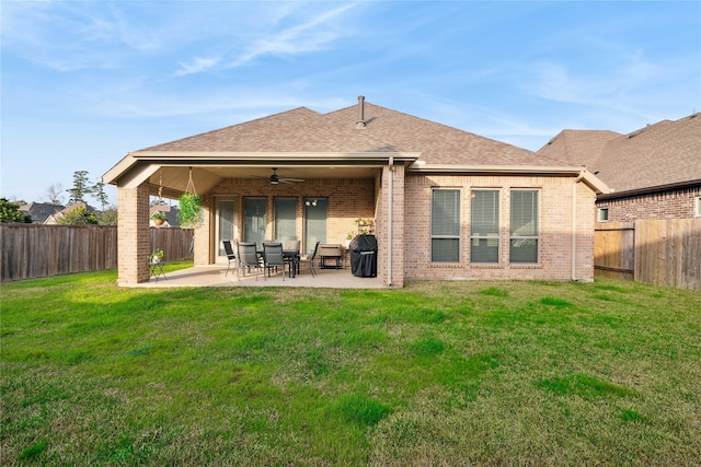 rear view of property featuring ceiling fan, a patio, and a lawn