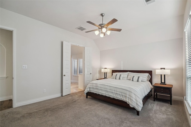 bedroom with ceiling fan, ensuite bathroom, vaulted ceiling, and dark colored carpet