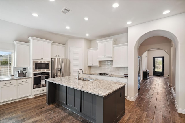 kitchen featuring sink, a kitchen island with sink, stainless steel appliances, light stone countertops, and white cabinets