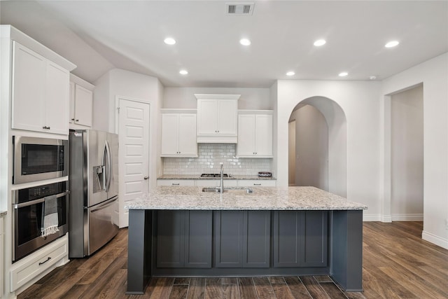 kitchen featuring white cabinetry, an island with sink, sink, stainless steel appliances, and light stone countertops