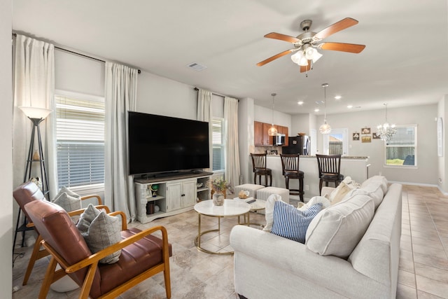 living room featuring light tile patterned floors and ceiling fan with notable chandelier