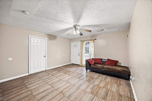 living area with ceiling fan and a textured ceiling