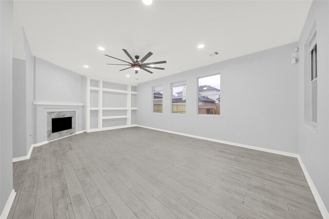 unfurnished living room featuring ceiling fan, a high end fireplace, and light hardwood / wood-style floors