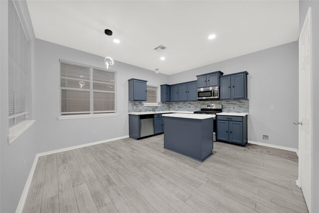 kitchen featuring tasteful backsplash, stainless steel appliances, a center island, and light wood-type flooring