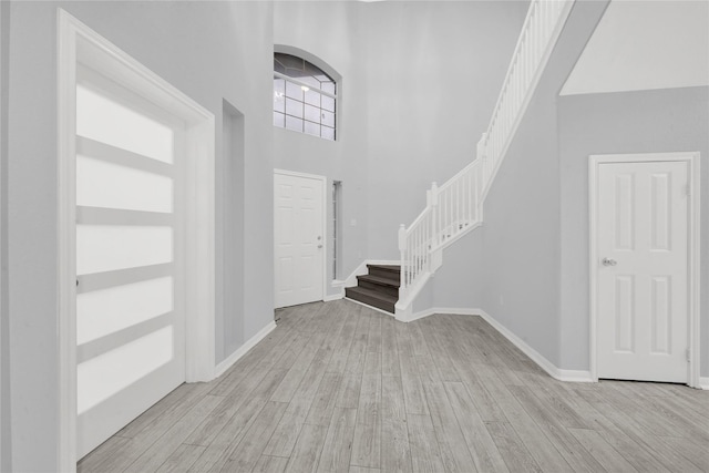 foyer entrance with light hardwood / wood-style floors and a high ceiling