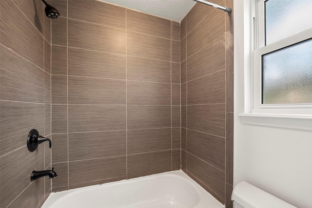 bathroom featuring toilet and tiled shower / bath combo