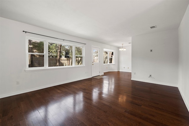 unfurnished living room featuring dark wood-type flooring and a chandelier