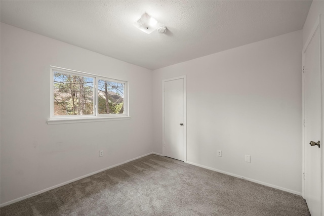 carpeted empty room featuring a textured ceiling