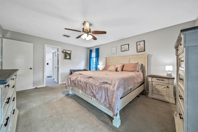 carpeted bedroom with ceiling fan and a textured ceiling