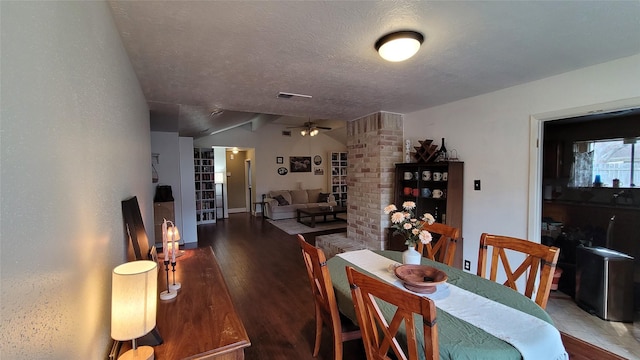 dining area featuring vaulted ceiling, ceiling fan, a textured ceiling, and dark hardwood / wood-style flooring