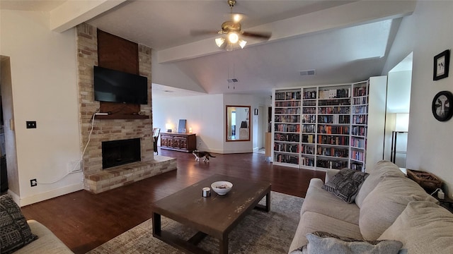 living room with dark wood-type flooring, a large fireplace, ceiling fan, and lofted ceiling with beams