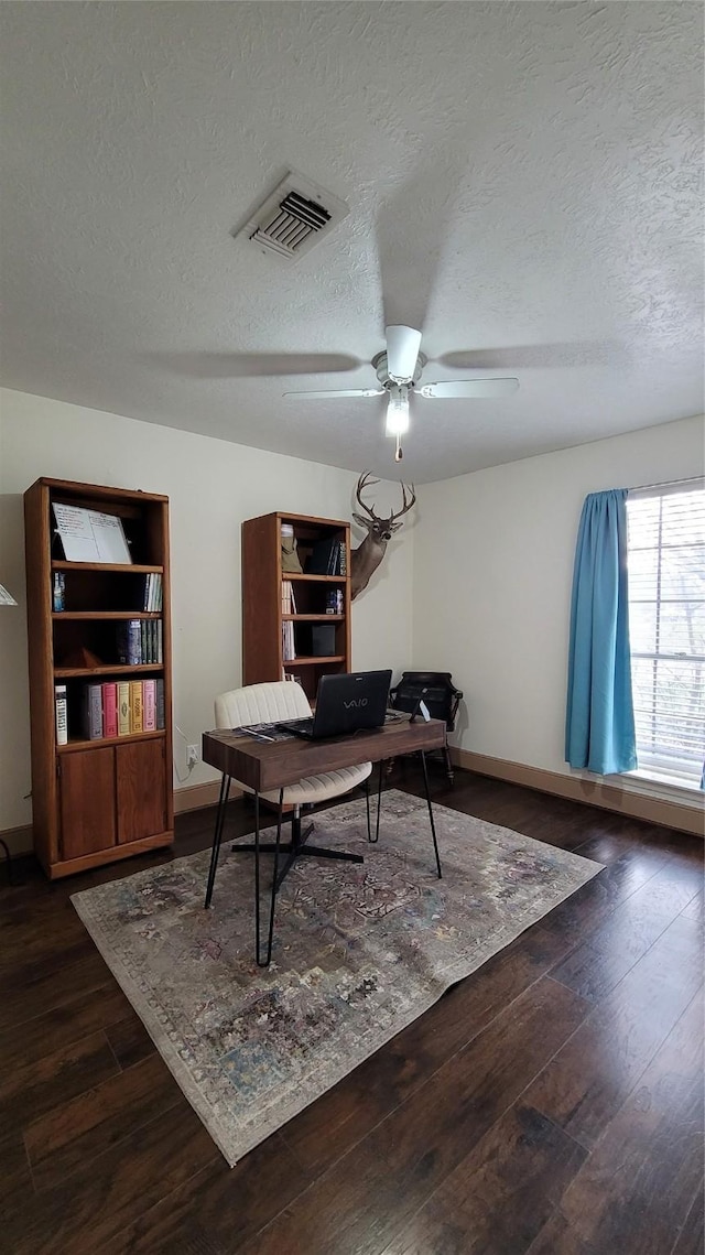 home office with ceiling fan, dark hardwood / wood-style flooring, and a textured ceiling