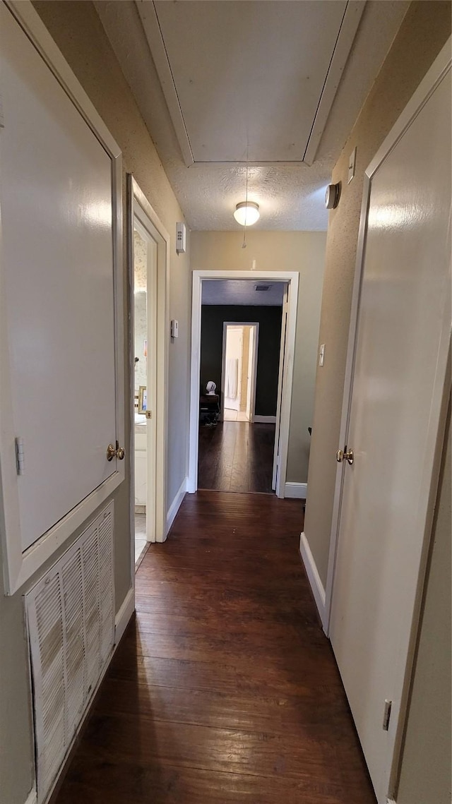 hallway with dark wood-type flooring and a textured ceiling