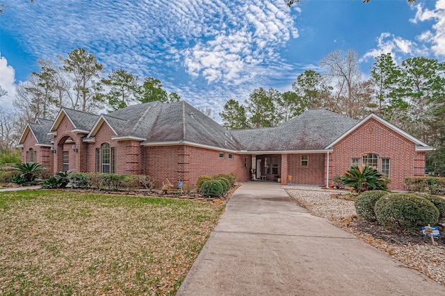 view of front of house with a front yard, concrete driveway, and brick siding