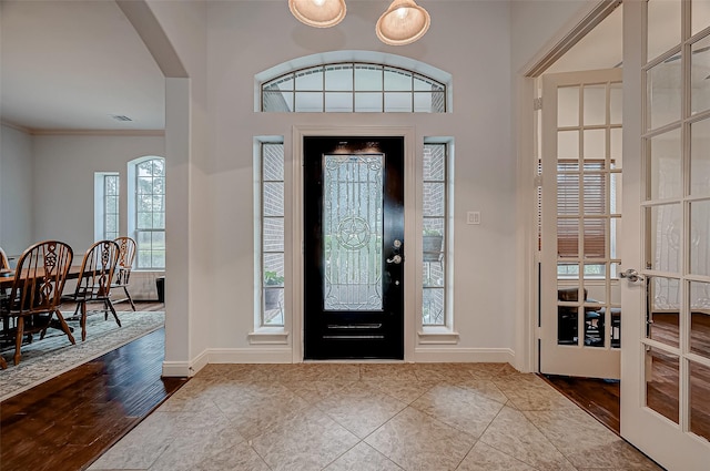 entrance foyer featuring arched walkways, french doors, visible vents, wood finished floors, and baseboards