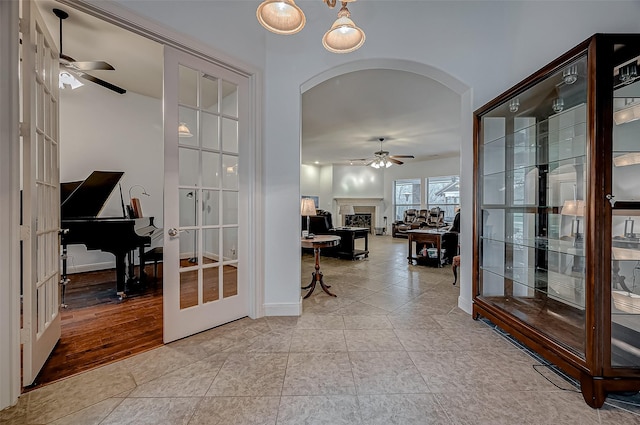 hall with light tile patterned floors, french doors, and arched walkways