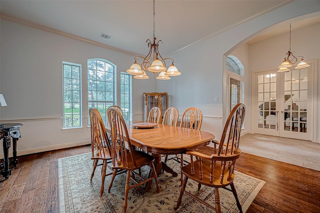 dining room featuring arched walkways, crown molding, visible vents, wood finished floors, and baseboards