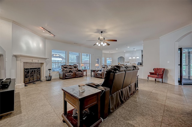 living area with a wealth of natural light, a fireplace, arched walkways, and crown molding