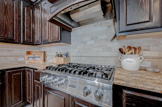 kitchen featuring wall chimney exhaust hood, stainless steel gas cooktop, backsplash, and dark brown cabinets