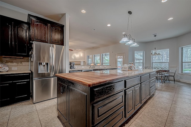 kitchen with decorative backsplash, stainless steel fridge with ice dispenser, butcher block counters, a center island, and dark brown cabinets