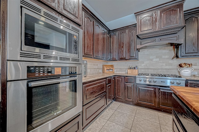 kitchen with appliances with stainless steel finishes, dark brown cabinetry, and custom range hood