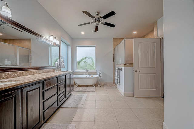 full bath featuring double vanity, a freestanding bath, a sink, and tile patterned floors