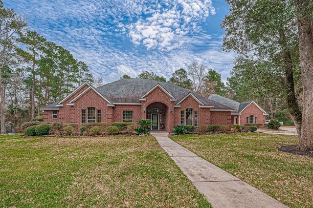 view of front of home featuring brick siding, roof with shingles, and a front yard