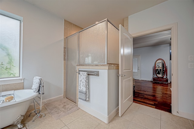 bathroom featuring tile patterned flooring, a soaking tub, a shower stall, and baseboards