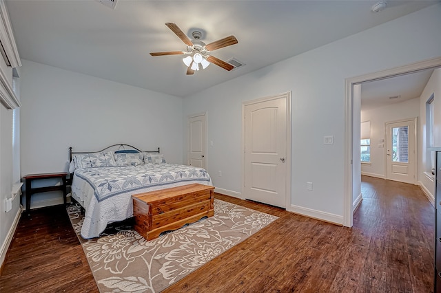 bedroom with dark wood-style floors, visible vents, baseboards, and a ceiling fan