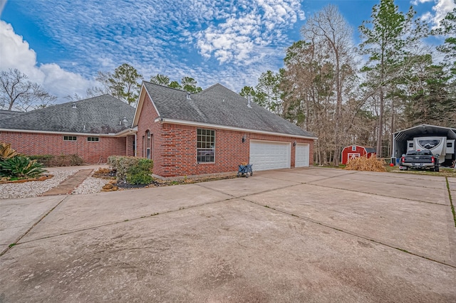 view of side of property featuring an attached garage, concrete driveway, brick siding, and a shingled roof