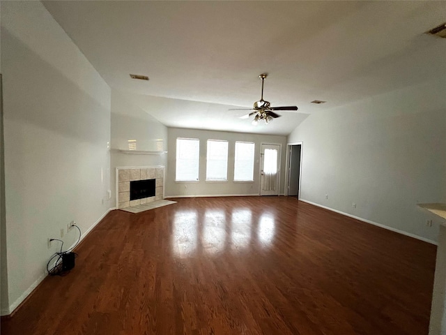 unfurnished living room with dark wood-type flooring, ceiling fan, vaulted ceiling, and a tile fireplace