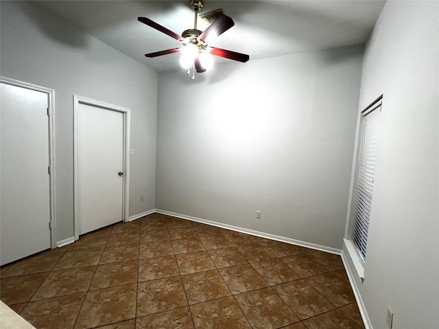 unfurnished bedroom with dark tile patterned floors, multiple closets, and ceiling fan