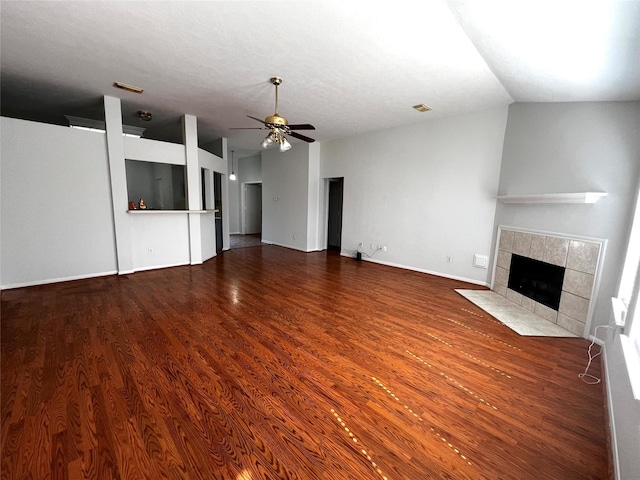 unfurnished living room with a tiled fireplace, hardwood / wood-style flooring, vaulted ceiling, and ceiling fan