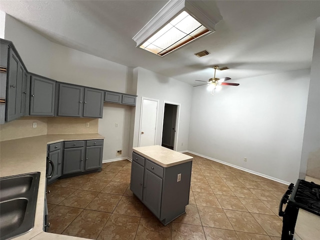 kitchen with a kitchen island, sink, gray cabinetry, and black gas stove