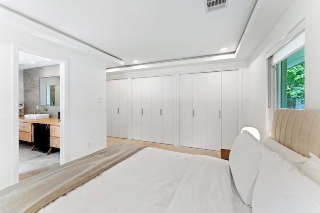 bedroom with sink, two closets, and ensuite bath