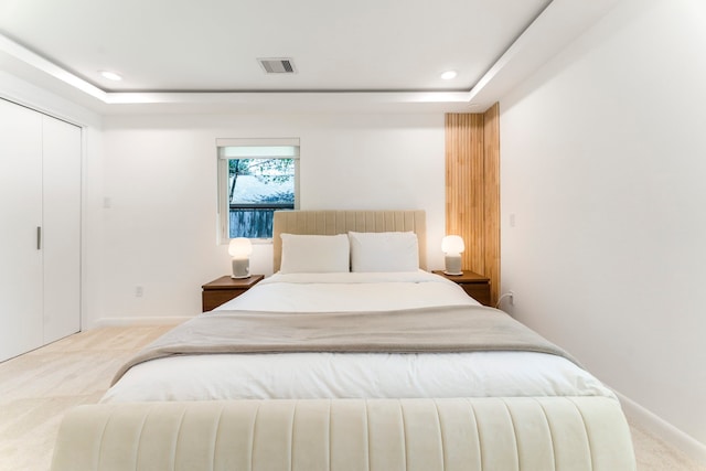 bedroom featuring light colored carpet and a tray ceiling