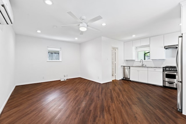 kitchen with stainless steel appliances, white cabinetry, an AC wall unit, and dark hardwood / wood-style flooring