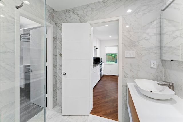 bathroom featuring hardwood / wood-style floors, a shower, tile walls, and vanity