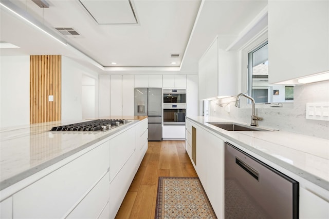 kitchen featuring stainless steel appliances, white cabinetry, sink, and decorative backsplash