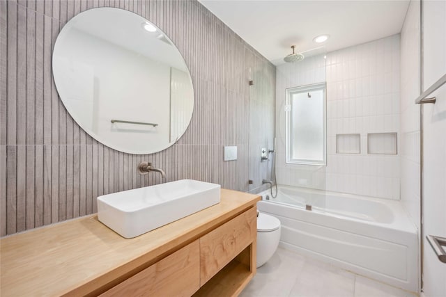 full bathroom featuring toilet, tiled shower / bath, tile walls, vanity, and tile patterned flooring