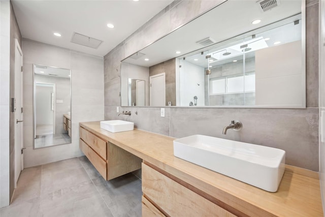 bathroom featuring vanity, a shower with shower door, and tile walls