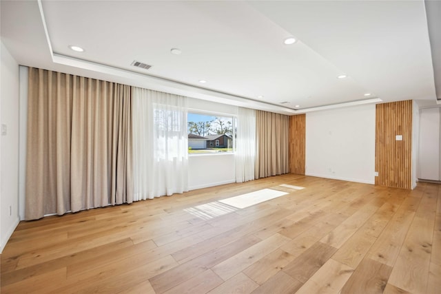 unfurnished room featuring a tray ceiling and light hardwood / wood-style flooring