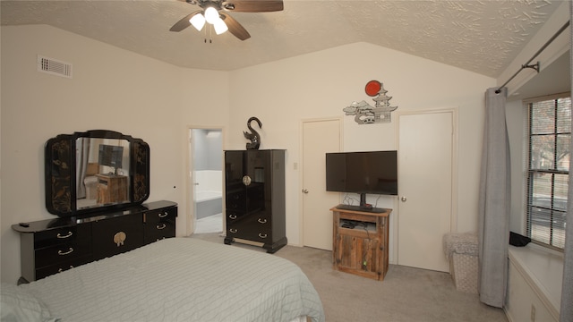 bedroom with lofted ceiling, connected bathroom, light carpet, and a textured ceiling