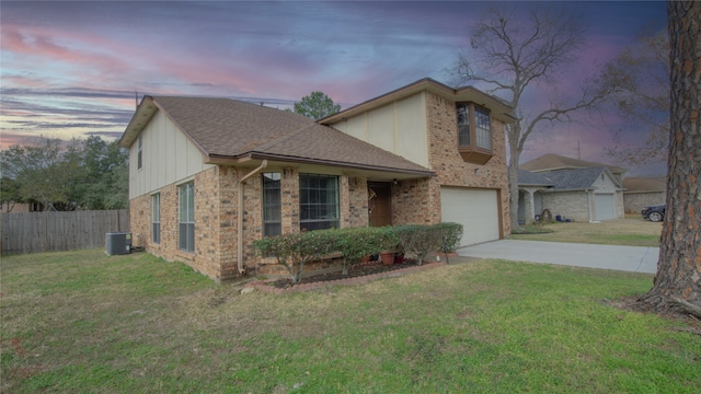 view of front of house with a garage, a lawn, and central air condition unit