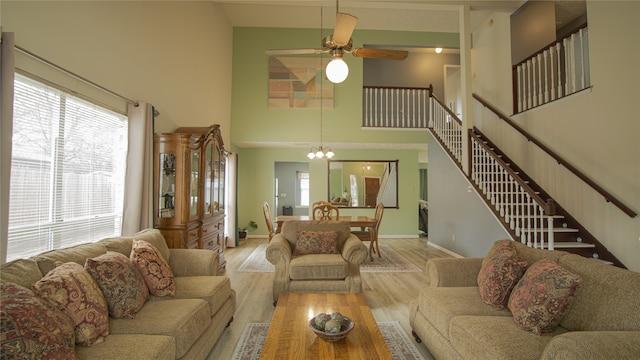 living room featuring a towering ceiling, light hardwood / wood-style flooring, and ceiling fan